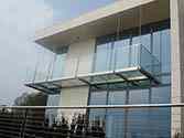 Hanging balcony with steel construction, glass flooring and frameless glass balustrade with stainless top handrail.