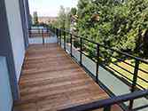 Balcony with steel construction, wooden boards and railings with glass infill