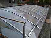Roof over driveway to the underground car park made of smooth, transparent polycarbonate plates mounted on supporting structure from powder painted galvanized steel profiles