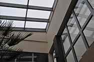 Glass roof covering a hothouse in the office building. Glass panels put on top of a galvanized steel frame mounted to the roof.