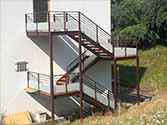 External steel staircase with wooden boards and railings with glass infill.