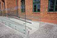 Frameless glass balustrade with stainless steel double handrail on wheelchair ramp