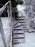 Stainless steel spiral stairs with steps from aluminum sheet. Railing with stainless steel handrail and posts