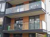 Balcony glass balustrade with steel handrail and posts. Glass panels mounted with standoffs from stainless steel