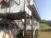 Staircase and balcony with steel support structures, wooden boards and railings with glass infill
