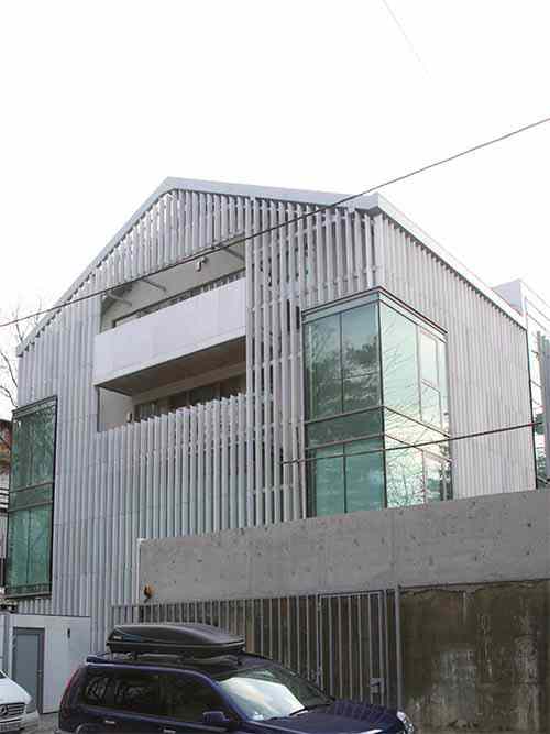 Façade covered with white marble elements mounted to galvanized steel frame