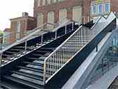 Staircase from steel sheets with steps from steel grid, stainless steel railing